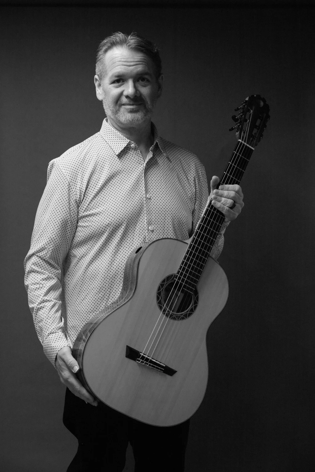 Black-and-white portrait of Christopher holding his classical guitar